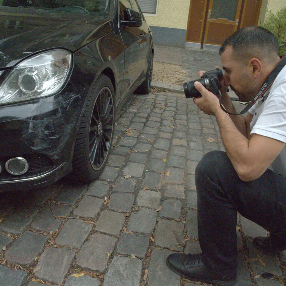Kfz Gutachter Reinickendorf dokumentiert Unfallschaden an schwarzem Fahrzeug mit Kamera