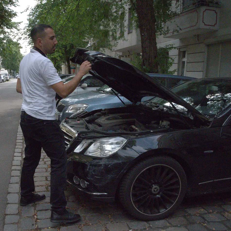 Kfz Gutachter Reinickendorf überprüft Fahrzeugmotor nach Unfall auf offener Straße